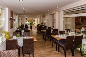 a dining room with tables and chairs and windows at Hotel Neptun in Schillig