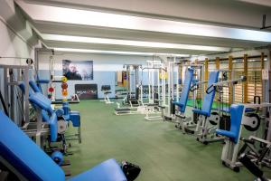 une salle de sport avec des rangées de machines à bande de roulement bleue dans l'établissement Hotel Brinje, à Zreče