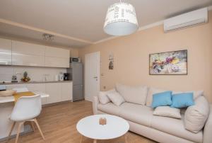 a living room with a white couch and a kitchen at Apartman Mate Luka in Makarska