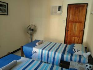 a bedroom with two beds and a fan and a door at Mingche Apartment in Panglao