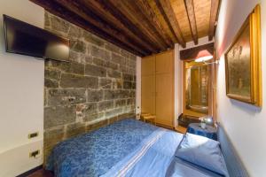 a bedroom with a blue bed and a stone wall at Affittacamere Bed and Breakfast San Lorenzo in Genova