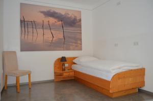 um quarto com uma cama, uma cadeira e um quadro em Pension zum Strell em Hollabrunn
