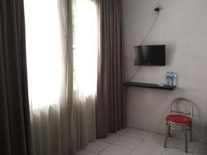 Habitación con ventana con silla y TV. en Maven Cilandak, en Yakarta