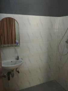 ein weiß gefliestes Bad mit einem Waschbecken und einem Spiegel in der Unterkunft Maven Cilandak in Jakarta