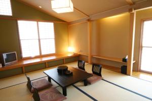 a living room with a table and chairs and windows at Hotel Taigakukan in Hakuba