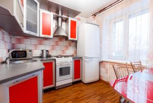 トムスクにある2к квартира в Ленинском районеのキッチン(赤と白の電化製品、テーブル付)