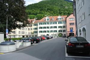 una strada di città con auto parcheggiate di fronte agli edifici di Hotel Drei Könige a Coira