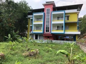 ein farbenfrohes Haus mit Garten davor in der Unterkunft EN Jays Residency (Service Apartments) in Kottayam