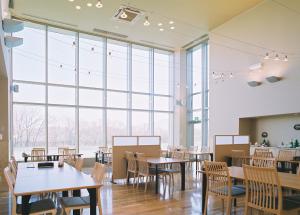 a restaurant with tables and chairs and large windows at Kiyosato Onsen Hotel Ryokuseisou in Kiyosato