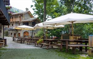 a group of picnic tables with umbrellas in front of a building at Agriturismo Valliera in Castelmagno