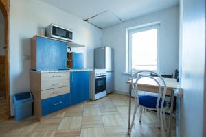 a kitchen with blue cabinets and a table and a chair at Svečiuose pas Aldoną in Druskininkai