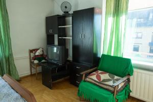 a living room with a green chair and a tv at Svečiuose pas Aldoną in Druskininkai