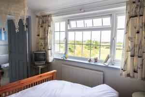 a bedroom with a bed and a window and a television at The White House in Padstow