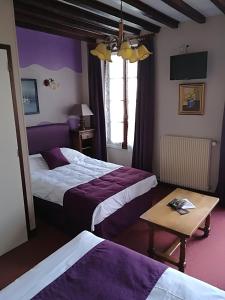 Habitación de hotel con 2 camas y mesa en Hostellerie Saint Martin- Logis Hôtel et Restaurant en Creully