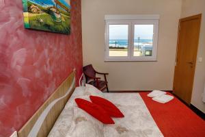 a bedroom with a bed with red pillows and a window at Muxia Mare in Muxia