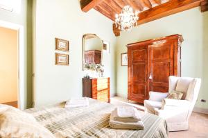 um quarto com uma cama, uma cadeira e um espelho em Apartment Guinigi with Private Courtyard em Lucca