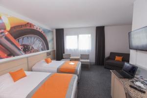 a hotel room with two beds and a flat screen tv at Hotel Le Paddock in Magny-Cours