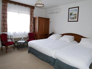 1 Schlafzimmer mit einem Bett, 2 Stühlen und einem Fenster in der Unterkunft Hotel-Spa & Restaurant Logis Domaine Langmatt in Murbach
