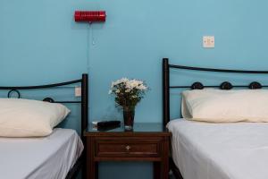 レティムノ・タウンにあるNeDa Rethymno Beach Studiosの青い部屋(ベッド2台付)とテーブルに花瓶を飾ります。