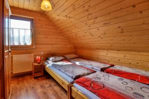 2 Betten in einem Blockhaus mit Fenster in der Unterkunft Domki w Istebnej in Istebna