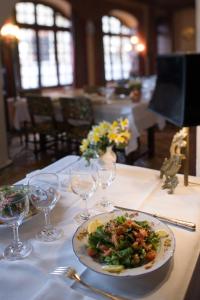 een bord eten op een tafel met wijnglazen bij Hostellerie du Vieux Pérouges in Pérouges