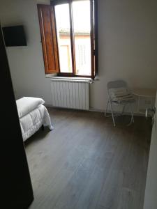 een slaapkamer met een bed, een raam en een stoel bij Alfredo's House in Siena