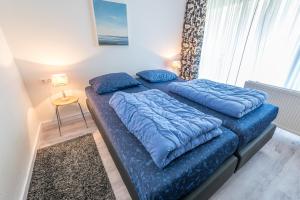 een slaapkamer met 2 bedden en blauwe kussens bij De Pelikaan Texel Appartementen in De Koog