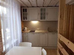 una cucina con armadi bianchi, tavolo e sedie di Guest House Ziedkalni a Dūmele