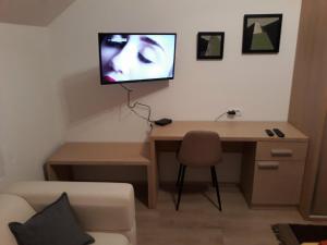 a room with a desk with a tv on the wall at Apartment Mašić in Sombor
