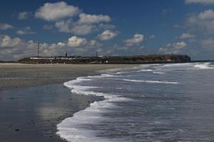 een strand met de oceaan en een vuurtoren op de achtergrond bij Rekwai 413 in Helgoland