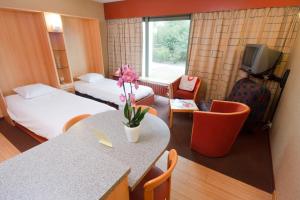 a hotel room with two beds and a table with flowers at Floreal Nieuwpoort in Nieuwpoort