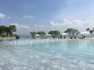 uma piscina com cadeiras brancas na água em HuiZhou HuaYangNian Seaview Guesthouse em Huidong