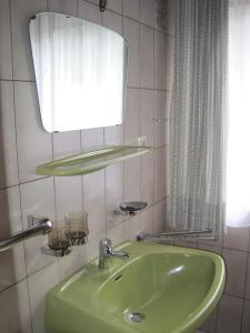 ein Badezimmer mit einem grünen Waschbecken und einem Spiegel in der Unterkunft Ferienwohnungen Tillian in Hermagor + 22 Fotos