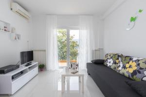 a white living room with a couch and a tv at Allegro in Rabac