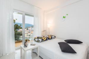 a white bedroom with a bed and a window at Allegro in Rabac