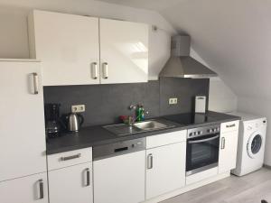 a kitchen with white cabinets and a sink and a stove at Apartment 28 o M in Castrop-Rauxel