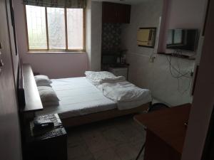 a small bedroom with a bed and a television at Service Apartments, Park Street, Calcutta in Kolkata