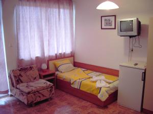 a bedroom with a bed and a chair and a tv at NELLY Guest House in Ravda