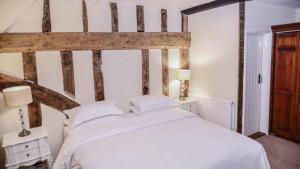 een slaapkamer met een groot wit bed met een houten hoofdeinde bij The Angel Hotel in Lavenham