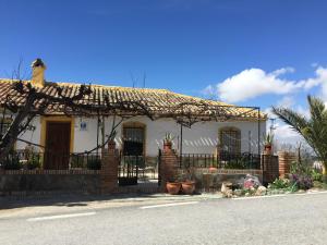 een wit huis met een hek ervoor bij Cortijo La Huerta in Pilas de Fuente Soto