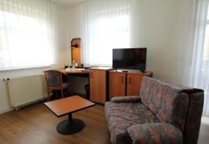 een woonkamer met een bank, een bureau en een televisie bij Hotel & Restaurant am Rosenhügel in Jüchsen
