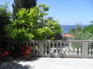 a white fence with flowers and the ocean in the background at Feel good apartment in Banjol