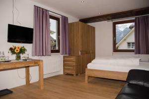 a bedroom with a bed and a desk and a tv at Hotel Daneu in Nüziders