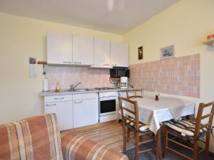 a kitchen with white cabinets and a table and chairs at Beautiful Apartment in Proseken with Garden in Proseken