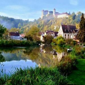 a town with a castle on a hill next to a lake at Old town center apartments on the Romantic Road in Harburg