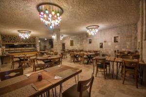 a restaurant with wooden tables and chairs and chandeliers at Hera Cave Suites in Göreme