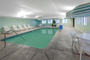 a swimming pool with chairs and a table and a table and chairs at Baymont by Wyndham Gaylord in Gaylord