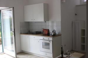 eine Küche mit weißen Schränken und einem Herd mit Backofen in der Unterkunft "NAR" Opatija center spacious 1 bedroom apt in Opatija