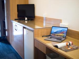 Un ordinateur portable est installé sur un bureau avec une télévision. dans l'établissement Sunnybank Star Hotel, à Brisbane