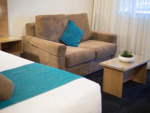 Habitación de hotel con sofá y silla en Sunnybank Star Hotel en Brisbane